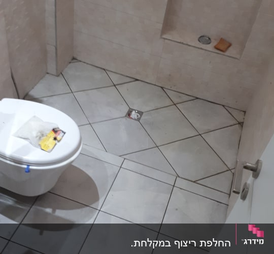 חדר אמבטיה עם אריחים חדשים, שירותים וכלים על הרצפה